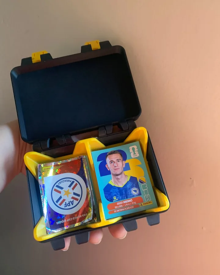 Maleta impressa em 3D aberta, com divisórias guardando figurinhas e cartas