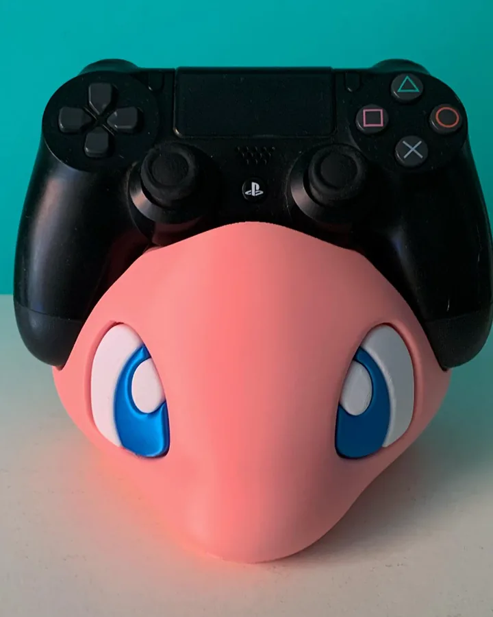 Suporte de controle de videogame em formato do Mew, em rosa, com um controle apoiado